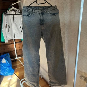 Grå jeansbyxor - Snygga grå jeansbyxor med en klassisk femficksdesign. De har en rak passform och är perfekta för en avslappnad stil. Byxorna har en knappgylf och bälteshällor.