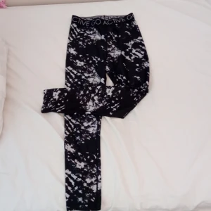 Svarta och vita träningebyxor med mönster - Hej, jag släjer dessa snygga leggings med ett unikt svartvitt mönster och texten 'GO ACTIVE' på midjan. Perfekta för träning eller en aktiv vardag. De har en tight passform och är tillverkade i ett stretchigt material för bästa komfort. Anledningen till att jag säger är att de är för små.