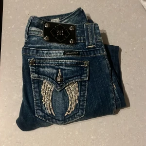 Blå jeans med broderade detaljer - Snygga blå jeans från Miss Me med unika broderade vingdetaljer på bakfickorna. Rak modell men inte skinny!! Sååååå snygga