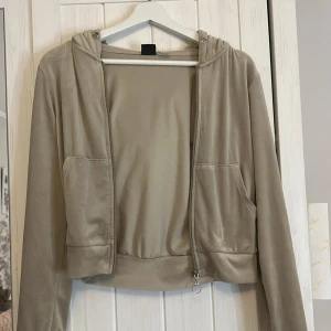 Beige hoodie från Gina Tricot - Säljer en beige hoodie från Gina Tricot i mjukt material. Den har dragkedja framtill och en praktisk huva. Perfekt för en avslappnad stil.