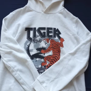 Vit hoodie med tigertryck - Säljer en cool vit, mycket skön samt häftig Hoddie. Hoodien har en klassisk design med långa ärmar och en bekväm huva. Perfekt för en avslappnad stil.