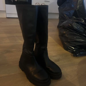 Svarta stövlar - Snygga svarta stövlar i fakeskinn med hög skaft. Perfekta för höst och vinter, dessa stövlar ger en stilren look och är lätta att matcha med olika outfits. Knappt använda 