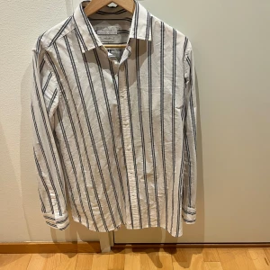 Randig skjorta från Massimo Dutti - Snygg vit skjorta med svarta ränder från Massimo Dutti. Storlek M, fler bilder går att fixa.