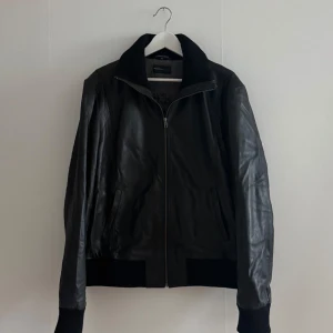 svart skinnjacka från RockandBlue - svart skinnjacka från Rockandblue med dragkedja framtill. Jackan har ribbade muddar vid ärmslut & nederkant samt krage. sitter som en L/XL.