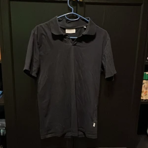 Svart kortärmad pikétröja från Lindbergh - Snygg svart pikétröja från Lindbergh i storlek S. 