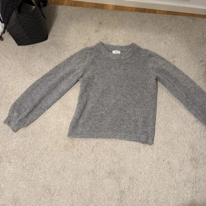 Grå stickad tröja från H&M - Mysig grå stickad tröja  med rund hals och långa ärmar. Perfekt för kyliga dagar.