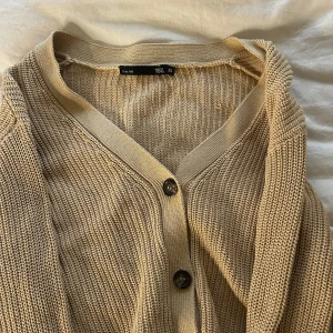 Beige stickad kofta från 157 - Säljer en mysig beige stickad kofta från Lager 157. 👼🫶🏻Det är en beige stickad kofta med bruna knappar framtill. Mysig att ha en sommarkväll eller nu under vintern☺️