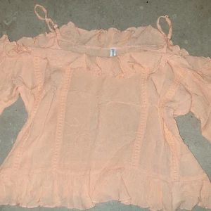 Persikofärgad blus - Säljer en söt persikofärgad blus från FB.Sister med volangdetaljer och offshoulder-design. Blusen har tunna axelband och är tillverkad i ett lätt och luftigt material, perfekt för varmare dagar.