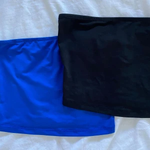 Svart och blå tubtopp - Två stilrena tubtoppar i svart och blått. Perfekta för en minimalistisk look, dessa toppar är enkla att matcha med olika outfits. De är tillverkade i ett mjukt och stretchigt material för en bekväm passform.