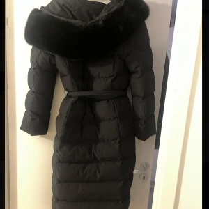 Svart vinterjacka med knyt - Svart vinterjacka med svart päls och knyt i midjan. Oanvänd, i storlek S. Köpt för 2500 säljs för 1000. 