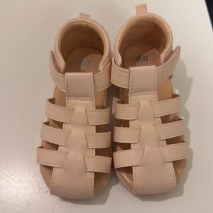Ljusrosa  sandaler från H&M - Söta ljusrosa sandaler med flera remmar och kardborreknäppning. Perfekta för varma sommardagar.