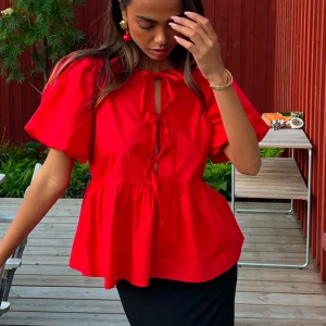 Röd blus med puffärmar och knytning - Använd en gång. Storlek 38. Passar s/m.