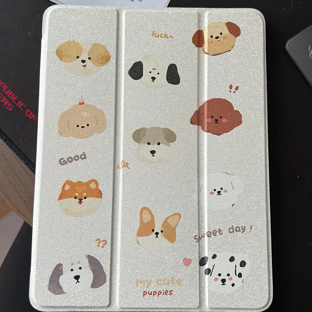 Charmigt iPad-fodral med olika hundmotiv och texten 'my cute puppies'. Fodralet har en glittrig yta och är designat för att skydda din enhet med stil. Perfekt för hundälskare! Gen 9. Muu.