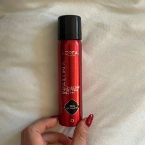 L'Oréal Paris Infallible Setting Mist - L'Oréal Paris Infallible 3-Second Setting Mist i en röd flaska med svart lock. Denna face mist lovar 36 timmars hållbarhet utan att smeta. Perfekt för att fixera sminket och hålla det fräscht hela dagen. Oanvänd 