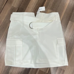 Vit cargo kjol med bälte - Jätte fin vit kjol med bälte. Kjolen är gammal från Gina tricot men är aldrig använd då den var för liten på mig. Prislappen sitter fortfarande kvar. Kjolen är i storlek 38. 
