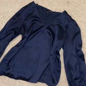 Marinblå blus från Vero Moda - Elegant marinblå blus från Vero Moda i ett glansigt material. Blusen har en v-ringad hals och långa ärmar, perfekt för fest 🎊 storleken är xs men passar bättre s-m skulle jag säga. Aldrig använd då den ej passade när jag fick den i julklapp🩷
