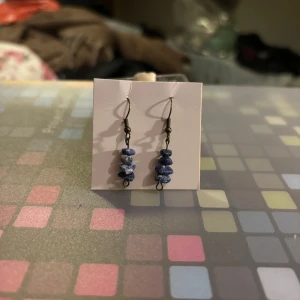 Blå örhängen med stenar - Snygga örhängen med blå stenar i en staplad design. Perfekta för att ge en färgklick till din outfit. De hänger från en enkel krok och är lätta att bära.