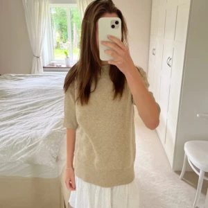 Beige stickad tröja från Vila - Säljer en stilren beige stickad tröja från Vila. Tröjan har en rund hals och korta ärmar, perfekt för en avslappnad look. Den är mjuk och bekväm, idealisk för både vår och höst. Ny med taggar kvar.