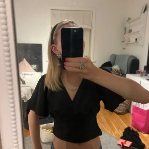 svart kroppad topp - supersnygg svart v-ringad topp med volang ärmar från??? köparen står för frakten!!