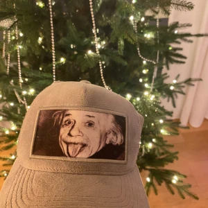 Velvet keps med Einstein - Snygg beige keps med ett ikoniskt tryck framtill. Kepsen har en justerbar baksida i mesh för bra ventilation och passform. Perfekt för en avslappnad stil.