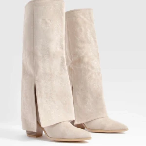 Beige knähöga boots - Lägg ett bud! Snygga beige stövlar i mocka med klack och spetsig tå. De har en stilren design med slitsdetaljer på skaftet. Det är helt nya! Har endast testat dom.