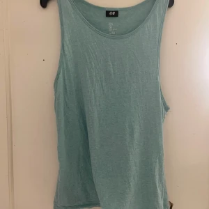 Ljusblå linnetopp från H&M - Säljer en ljusblå linnetopp från H&M. Perfekt för varma dagar med sin ärmlösa design och mjuka bomullsmaterial. Enkel och stilren för en avslappnad look.