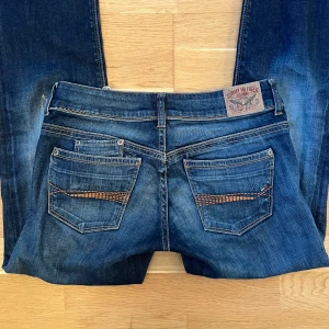 Fina lowrise jeans med vackra detaljer - Snygga lågmidjade Tommy Hilfiger jeans med broderade detaljer på bakfickorna. De är i rak, något bootcut passform som sitter supersnyggt! St W28 L32, vilket motsvarar S🌟🌟