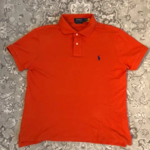 Orange RL piké - Säljer nu denna as fräscha orange piké med marinblå detaljer från Ralph Lauren| den är perfekt till en unik outfit och gör en sticka ut| den är i storlek M men passar mer som S| köpt i somras för 1050| vid några frågor eller funderingar är det bara att höra av sig!😮‍💨😁