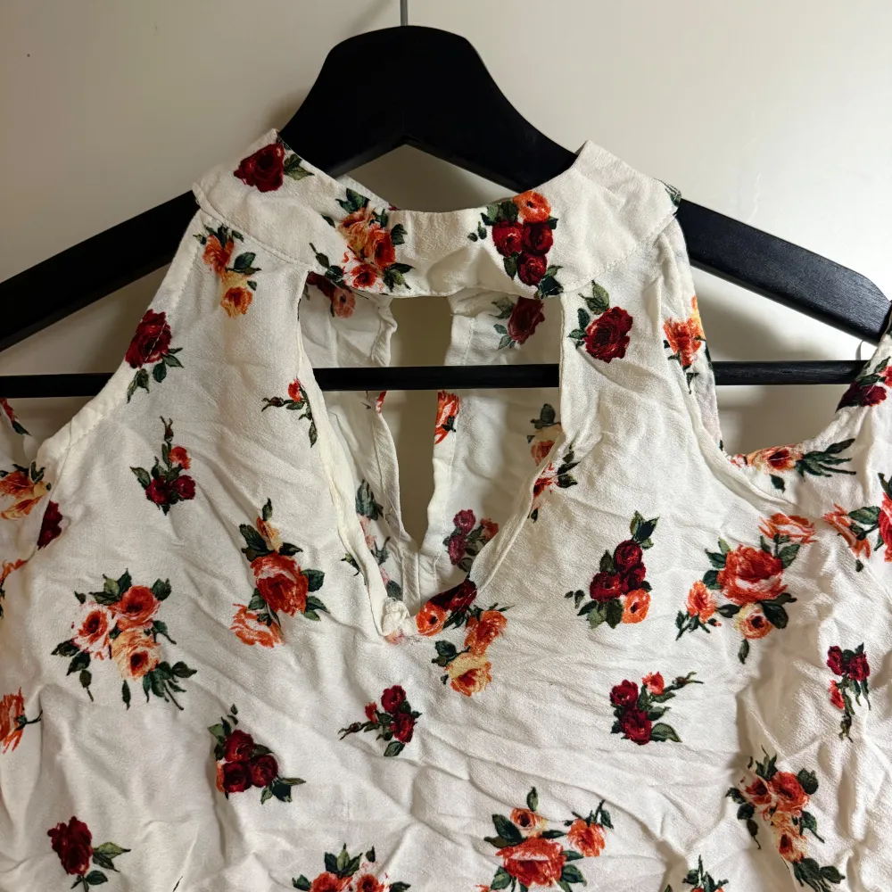 Säljer en vacker blommig blus från Mango i storlek S. Blusen är vit med ett färgglatt blommönster i rött och orange. Den har en v-ringad design och långa ärmar med öppna axlar. Perfekt för vår och sommar!. Yläosat.