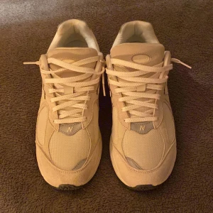 Beige sneakers från New Balance - Säljer ett par helt nya och stilrena beiga sneakers (modell, 2002R) från New Balance. Skorna har snörning och är tillverkade i syntetmaterial med en bekväm sula. Dem har dessutom en reflex, som är en cool extra detalj. Perfekta för en avslappnad stil. Pris kan diskuteras. Hör av dig om det finns frågor! 