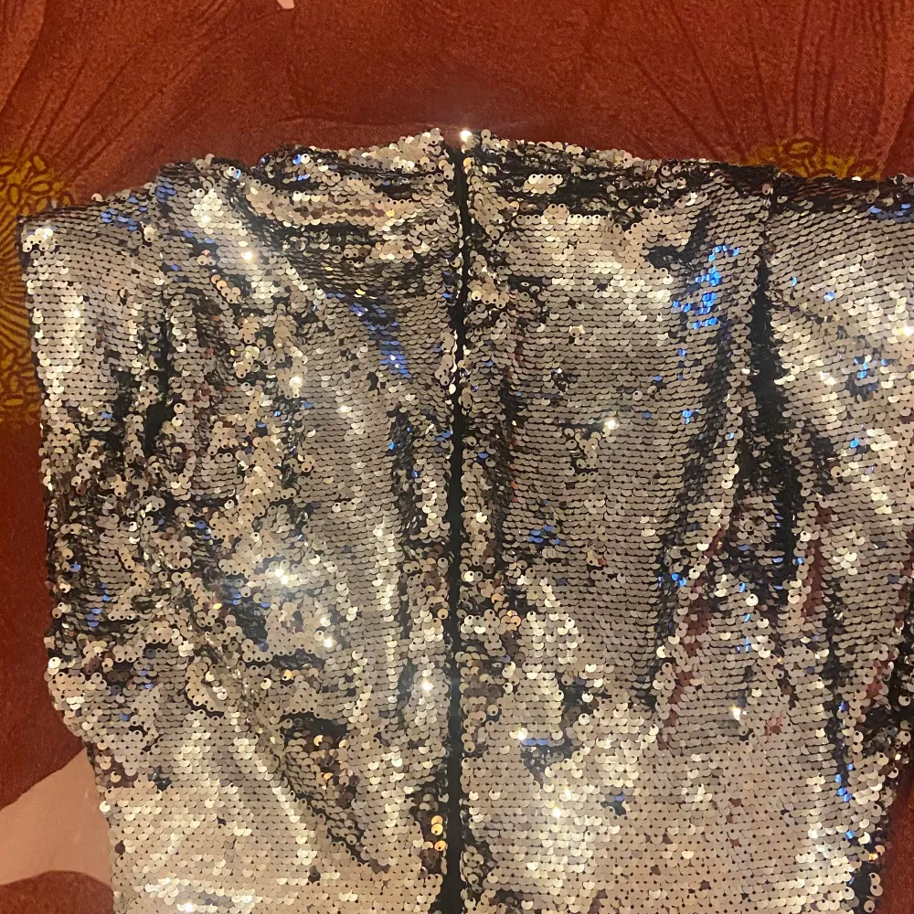 Snygg och glittrig klänning från H&M täckt med silverfärgade paljetter. Perfekt för en festlig kväll! Klänningen har en figurnära passform och är axelbandslös för en elegant look.. Mekot.