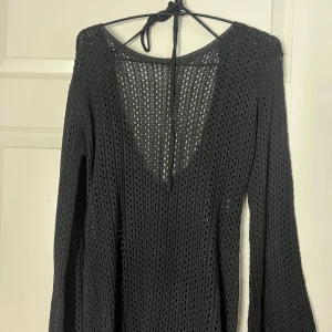 Svart stickad klänning - Snygg svart stickad klänning med lång ärm och knytband i nacken. 