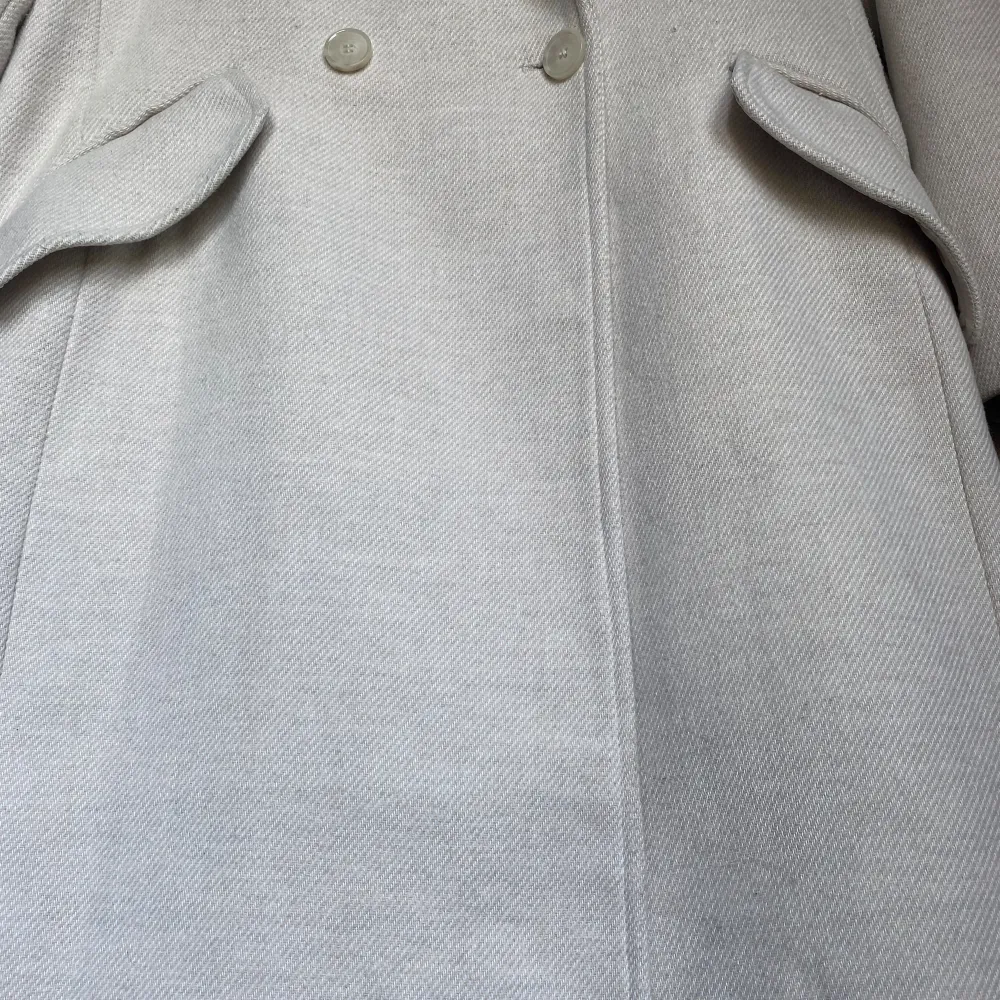 Beige kappa från H&M. De två sista bilderna visar färgen bäst. Fint skick. Lite nopprig på vissa ställen, men jag har använt noppborttagare så det är knappt märkbart. Den har ett märke (bild 4), men det döljs om man stänger kappan & är ganska diskret. Takit.