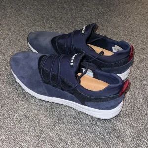 Skor - Skor i den finare typen. De är mörkblå med vit/svartsula och röda detaljer bak. Det är knappt använda och har storlek 42.