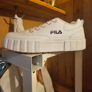Vita sneakers från Fila - Säljer ett par snygga vita sneakers från Fila. De har en chunky sula och klassisk snörning. Perfekta för en casual look och passar till det mesta i garderoben. Skorna är i nyskick endast testade.