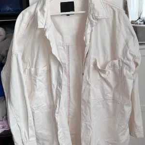 Säljer en stilren vit overshirt med långa ärmar och två stora fickor framtill. Perfekt för lager-på-lager-stil och passar både till vardags och lite mer uppklädda tillfällen. Skön och lätt att bära!