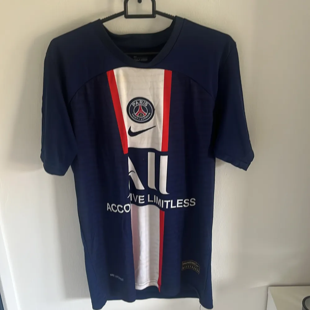 Säljer en snygg blå PSG fotbollströja från Nike med Mbappé och nummer 7 på ryggen. Tröjan har korta ärmar och är i Dri-FIT material för bästa komfort. Perfekt för alla PSG-fans!. T-shirts.