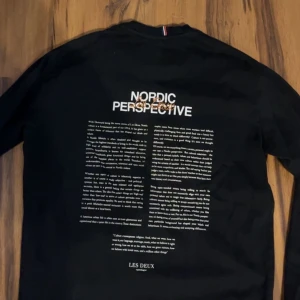 Svart långärmad tröja från Les Deux - Säljer en svart långärmad tröja från Les Deux med texten 'NORDIC PERSPECTIVE' tryckt på ryggen. Tröjan är perfekt för en casual look och passar bra till både jeans och chinos. Den är i bra skick och bekväm. Passar även storlek S