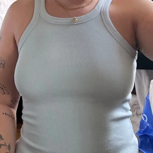 Ljusblå ribbad linnetopp - Säljer en snygg ljusblå ribbad linnetopp. Den är ärmlös och har en tight passform, perfekt för sommardagar eller som ett basplagg i garderoben. Toppen är enkel men stilren och kan matchas med nästan vad som helst!