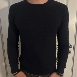 Mörkblå Finstickad Tröja från J.Lindeberg - Säljer en snygg Mörkblå kabel stickad tröja från J.Lindeberg. Den har en stilren design med ett diskret mönster och är perfekt för både höst och vinter. Tröjan är i så gott som nytt skick! Modellen är 182 cm och väger 75 kg. Pris går att diskuteras!