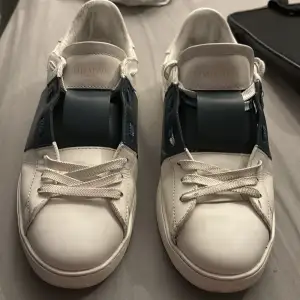 Säljer ett par snygga Valentino opens sneakers i vitt med en cool blå detalj över snörningen. Skorna är i skinn och har en klassisk design med vita snören. De är i bra skick. Perfekta för både vardag och fest!