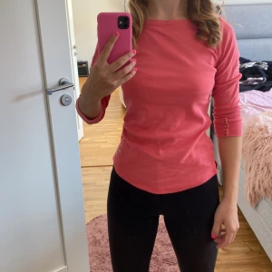 Röd topp från Gant - Säljer en snygg röd topp. Den har trekvartsärmar med knappar som en fin detalj. Perfekt för både vardag och lite finare tillfällen. Toppen är i ett mjukt och bekvämt material.