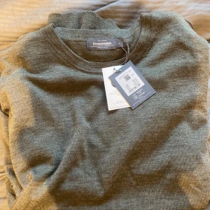 Grön ulltröja från Dressmann - Säljer en snygg och stilren grön tröja från Dressmann. Den är gjord av 100% merinoull vilket gör den supermjuk och perfekt för kyliga dagar. Tröjan har en klassisk passform med långa ärmar och rund hals. Perfekt för både vardag och lite finare tillfällen!