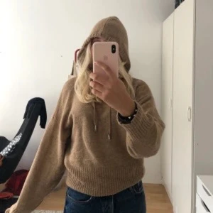 Beige stickad hoodie - Säljer en mysig beige stickad hoodie med långa ärmar och dragsko i huvan. Perfekt för kyliga dagar och ger en avslappnad stil. Passar bra till jeans eller leggings.