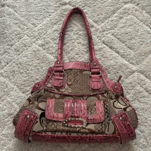 Snygg vårig väska! - Snygg handväska med unikt mönster i beige och brunt, kombinerat med rosa detaljer. Väskan har flera fack och dragkedjor för praktisk förvaring. Perfekt för att ge din outfit en färgklick! Aldrig använd, vet ej märket. 