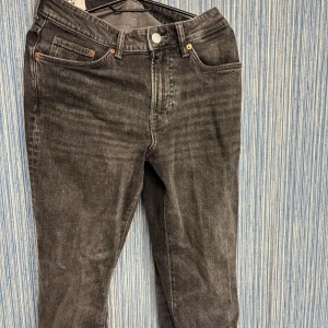 Mörkgråa jeansbyxor - Snygga svarta jeansbyxor med klassisk femficksdesign och knappgylf. Perfekta för en stilren look. Passar till många olika outfits. Storlek 30/32