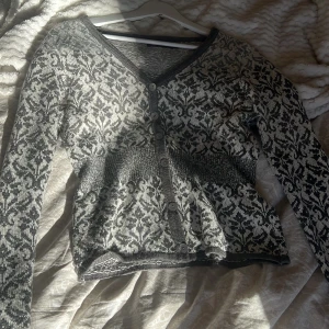 Gråmönstrad kofta från Indiska❤️‍🔥 - Säljer en stilren gråmönstrad kofta från Indiska. Koftan har ett vackert mönster i grått och vitt, med knappar framtill och långa ärmar!! Koftan är verkligen så vacker🥰🤍