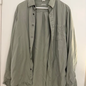 Grön skjorta med normal passform - Säljer en stilren grön skjorta med normal passform. Skjortan har långa ärmar och knappar framtill. Perfekt för en avslappnad look.