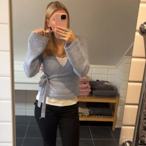 Ljusblå omlottkofta från Gina Tricot - Säljer en mysig ljusblå omlottkofta från Gina Tricot. Koftan har långa ärmar och ett knytband i midjan för en snygg passform. Använd en gång och inga defekter. Säljer då den inte är min stil riktigt.  Perfekt för kyligare dagar.😊