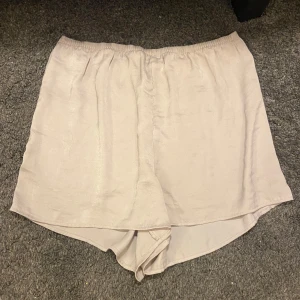 Beige/rosa shorts - Beige/rosa shorts i satin med elastisk midja. 